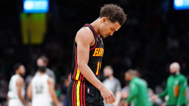 Trae Young walks to the bench with his head down.